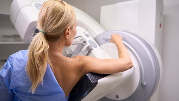 stock image of female patient undergoing 3D mammography in radiology room