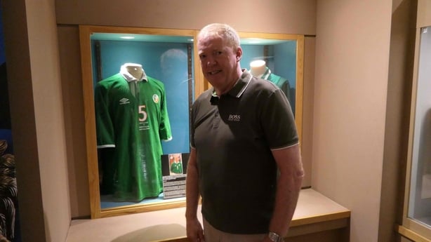 Stephen Staunton stands in front of a display case where he jersey is displayed