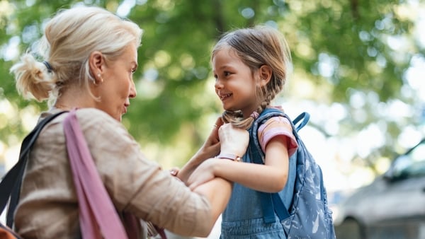 A touching moment as a mother helps her daughter get ready for school, embodying care, love, and support. Outdoors, highlighted by warm morning light and a cheerful atmosphere, this image captures family togetherness.