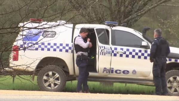 Two Australian police officers stand beside a police car