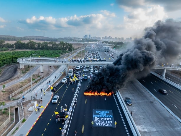 Traffic congestion and black smoke rising from burning tyres on a main road blocked by Israeli protesters calling for an end to the Gaza war