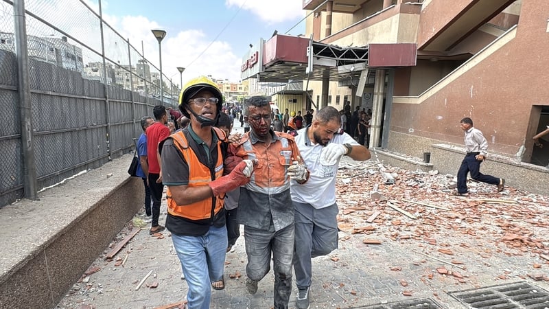Injured Palestinians are carried out of the Nasser Hospital by local residents following Israeli attacks on the Nasser Medical Complex in Khan Younis