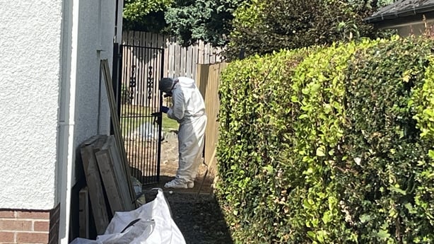 A man dressed in white forensic overalls works at a crime scene