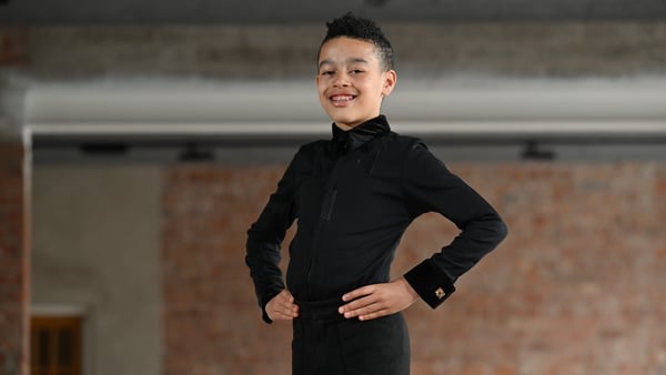 A boy poses for a photo wearing a black Irish dancing outfit