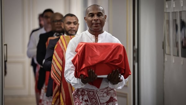 A man carries a box covered by a red cloth during the ceremony in which France returned a king's skull to Madagascar.