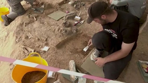 An archaeologist works at a dig site with tools