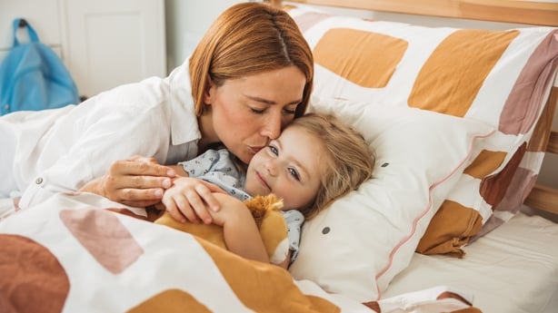 Mother putting daughter to sleep in kids bedroom