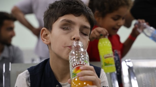 A boy with facial injuries drinks from a bottle of juice
