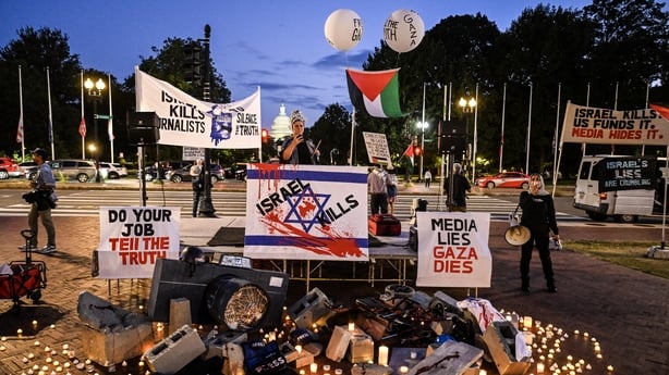Broken cameras, helmets marked with "PRESS," blood-stained protective vests, and scattered cinder blocks on the ground surrounded by candles in front of Union Station in Washington, D.C