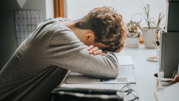 A young boy resting his head on a desk