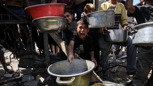 Palestinians children, who are struggling to access food due to Israel's blockade and ongoing attacks on the Gaza Strip, wait in line to receive hot meals distributed by the charity organization in Gaza City, Gaza