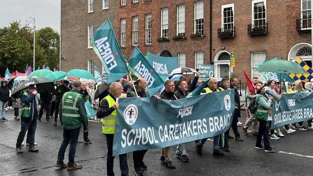 A large group of School secretaries and caretakers march through Dublin's city centre with banners