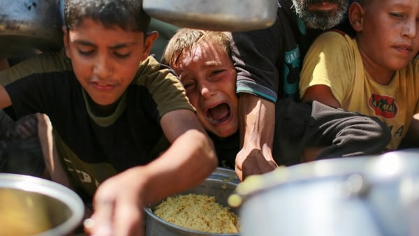 A young boy cries as people jostle together for get rice from a charity kitchen in Gaza