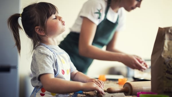 Cute little girl baking at home with mom, young mother and daughter making cookies in the kitchen.