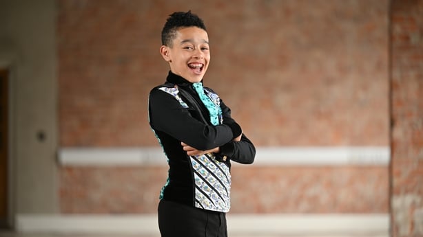 Young Irish Dancer Tomi Elemide smiles as he poses in his costume.