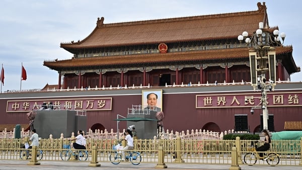 People ride past a portrait of the late communist leader Mao Zedong on Tiananmen Square