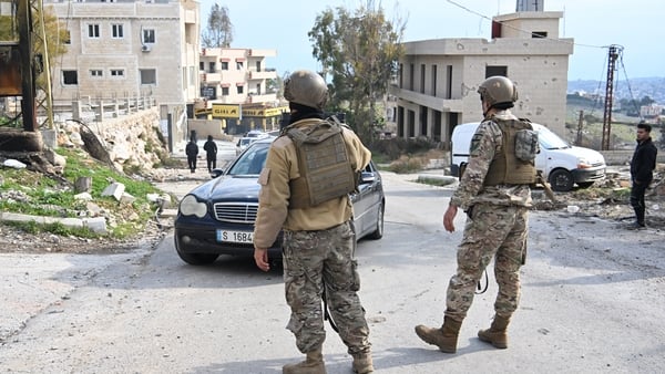 Two soldiers watch as a car passes by them in Lebanon
