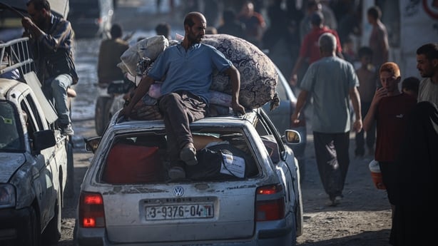 A man sites on top of a car as it moves through crowds in gaza