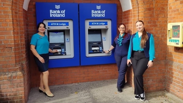 Two female Bank of Ireland staff members outside two new ATMs
