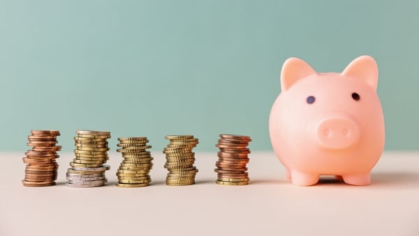 Stacks of euro coins next to a pink piggy bank