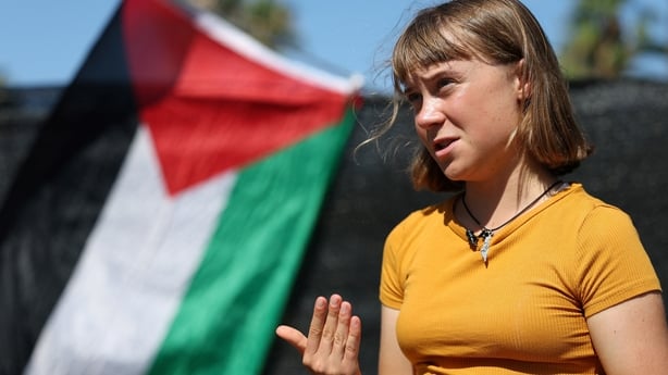 A person speaks in front of a Palestinian flag 