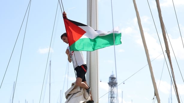 An activist puts a Palestinian flag on a boat