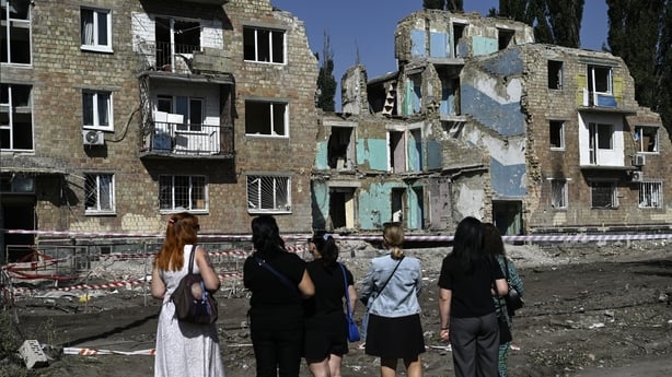 Local residents stand in front of the residential building heavily damaged three days ago during a large-scale Russian drone and missile attack, in Kyiv