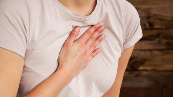 A stock image of a woman holding her hand to her chest