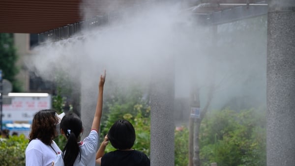 Pedestrians under a cooling mist in Ginza district during high temperatures in Tokyo