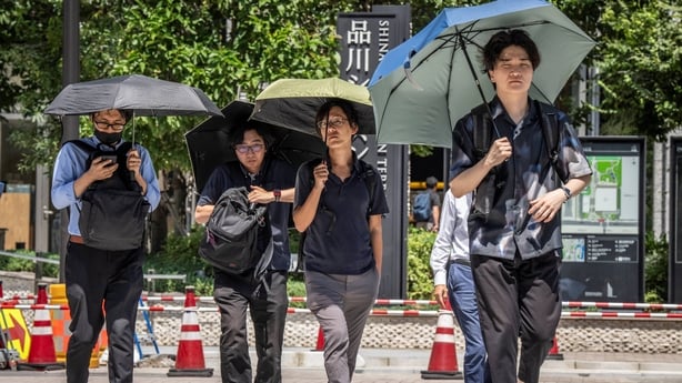 People use umbrellas to shield from hot sun in Tokyo
