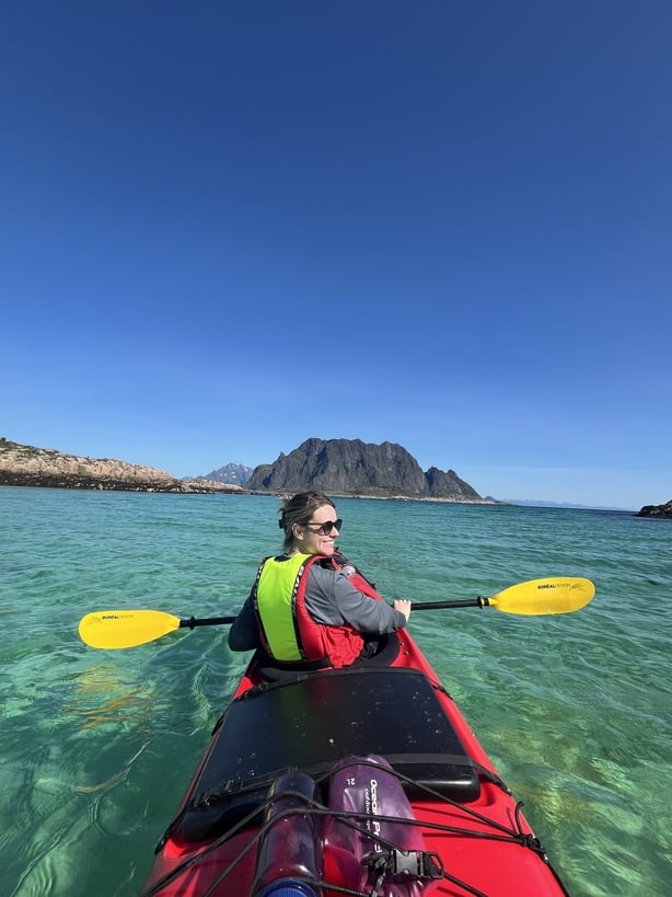 A photo of a woman kayaking in clear water