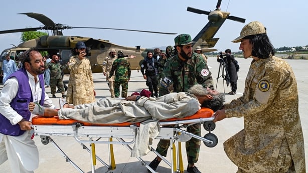 Afghan volunteers and Taliban security personnel carry an earthquake victim