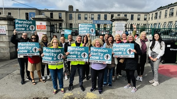 A group of people hold signs on a picket line outside a school