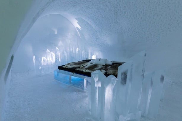 An ice hotel with a bed in the middle of the room