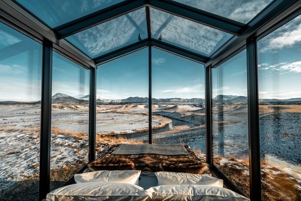 A glass cabin that overlooks a winter landscape