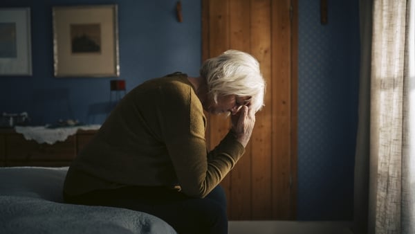 Older woman with her head in her hand, looking sad