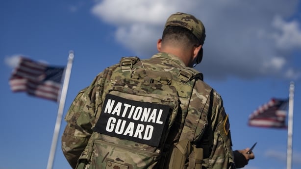 A member of the US National Guard on patrol with flags flying nearby