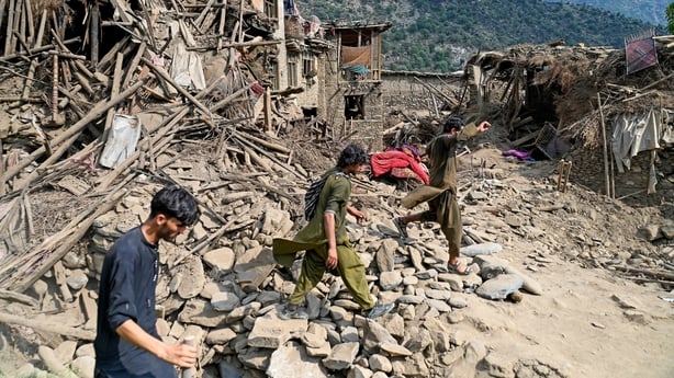 Men walk past houses destroyed in a 6 magnitude earthquake in Afghanistan