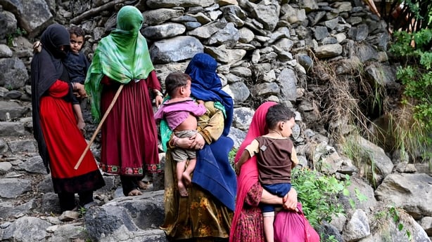 Afghan women and their children walking through a rocky area in Kunar after the earquake.