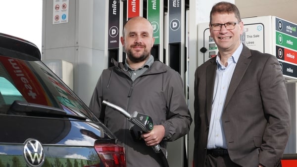 Two men standing at a fuel pump at a Circle K forecourt