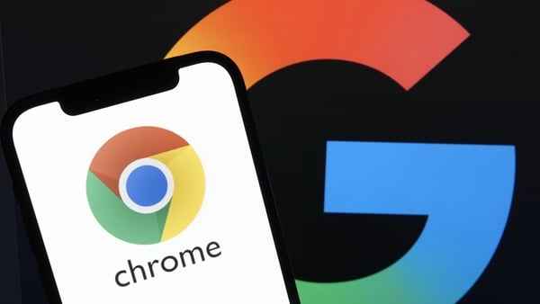 Google Chrome app icon displays on a smartphone with the Google logo in the background