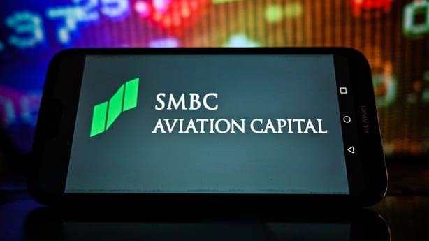 Photo illustration of the SMBC Aviation Capital logo on a smartphone with stock market percentages in the background