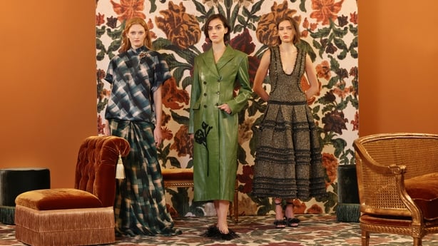 Three women pose in front of a floral backdrop 