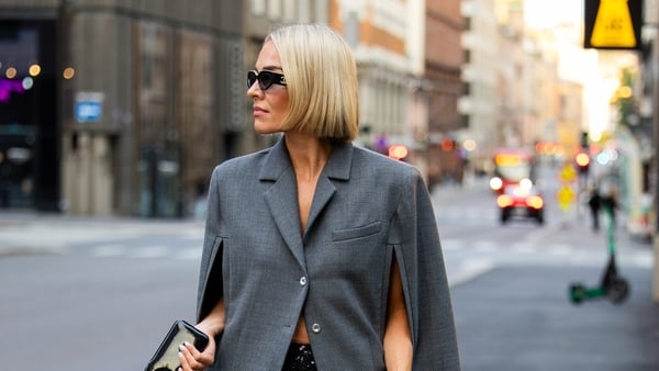 OSLO, NORWAY - AUGUST 26: A guest wears grey cape / coat with slits, brown bag, transparent skirt during Oslo Fashion Week on August 26, 2025 in Oslo, Norway. (Photo by Christian Vierig/Getty Images)