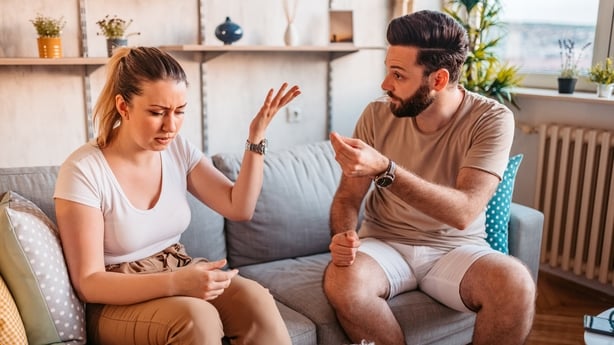Young heterosexual couple are quarreling while sitting on couch at home.