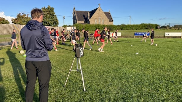 A man looks at a screen while a device takes data of people play GAA