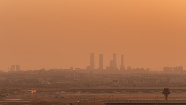 a skyline of tall buildings in the distance with smog in the air