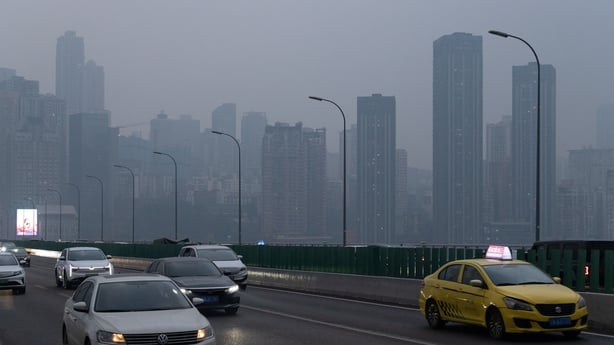 Cars are seen driving on a bridge in China with smog in the background