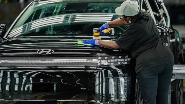 A female woman polishes a car in an manufacturing plant 