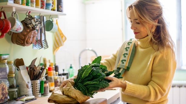 A woman taking kale out of a bag to cook with